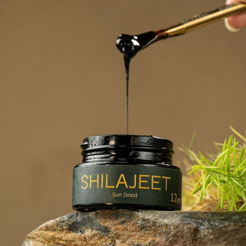 Pure Himalayan Shilajit in a jar being lifted with a stick, showcasing its natural resin texture.